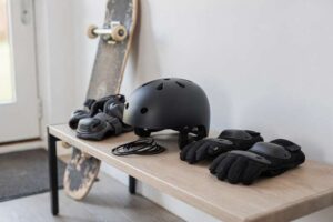 Ragazzo protetto da casco, ginocchiere e polsiere mentre pratica skateboard su una rampa.