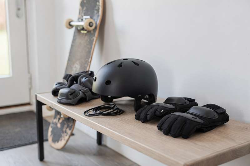 Ragazzo protetto da casco, ginocchiere e polsiere mentre pratica skateboard su una rampa.