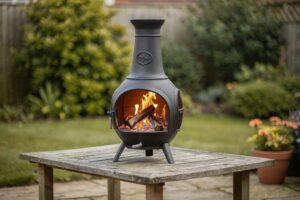 Persona che gode del calore di una ciminiera da giardino in una sera di relax con amici all'aperto.