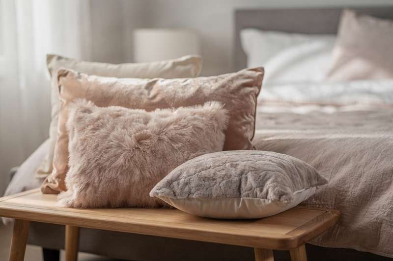 Ragazza che abbraccia un cuscino di peluche morbido mentre riposa comodamente nel suo letto.