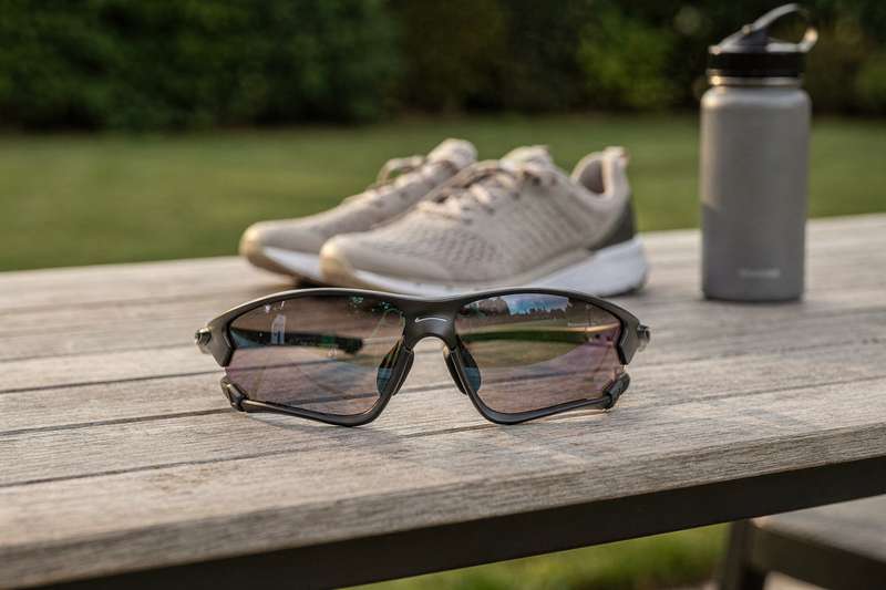 Atleta con occhiali da sole sportivi durante una corsa all'aperto in una giornata soleggiata.