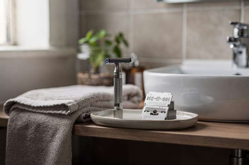 Uomo che si rade con attenzione usando una lametta da barba di qualità nel bagno di casa.