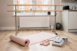 Una ballerina esegue esercizi di danza classica a casa con la sbarra di allenamento e lo specchio riflettente.
