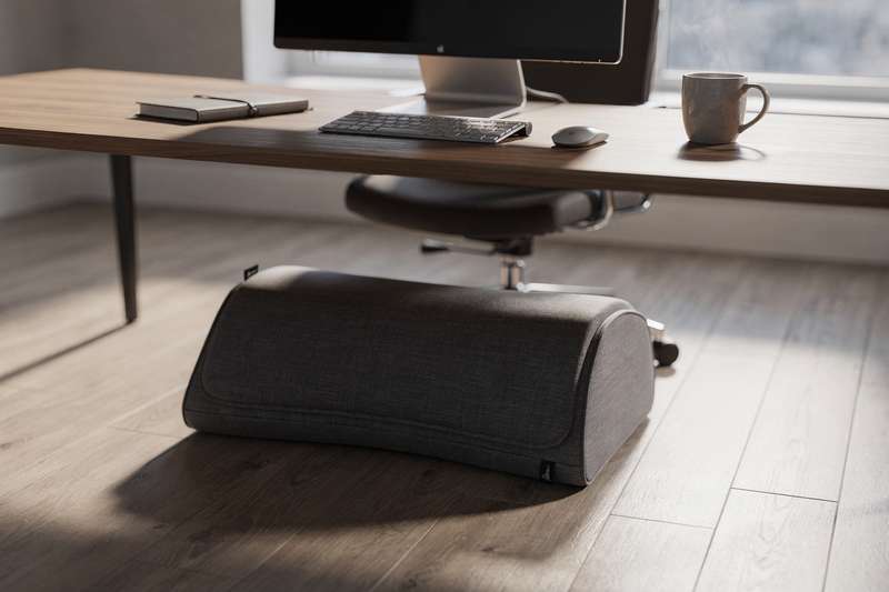 Una persona seduta alla scrivania dell'ufficio poggia i piedi su un riscaldatore mentre lavora al computer durante l'inverno.